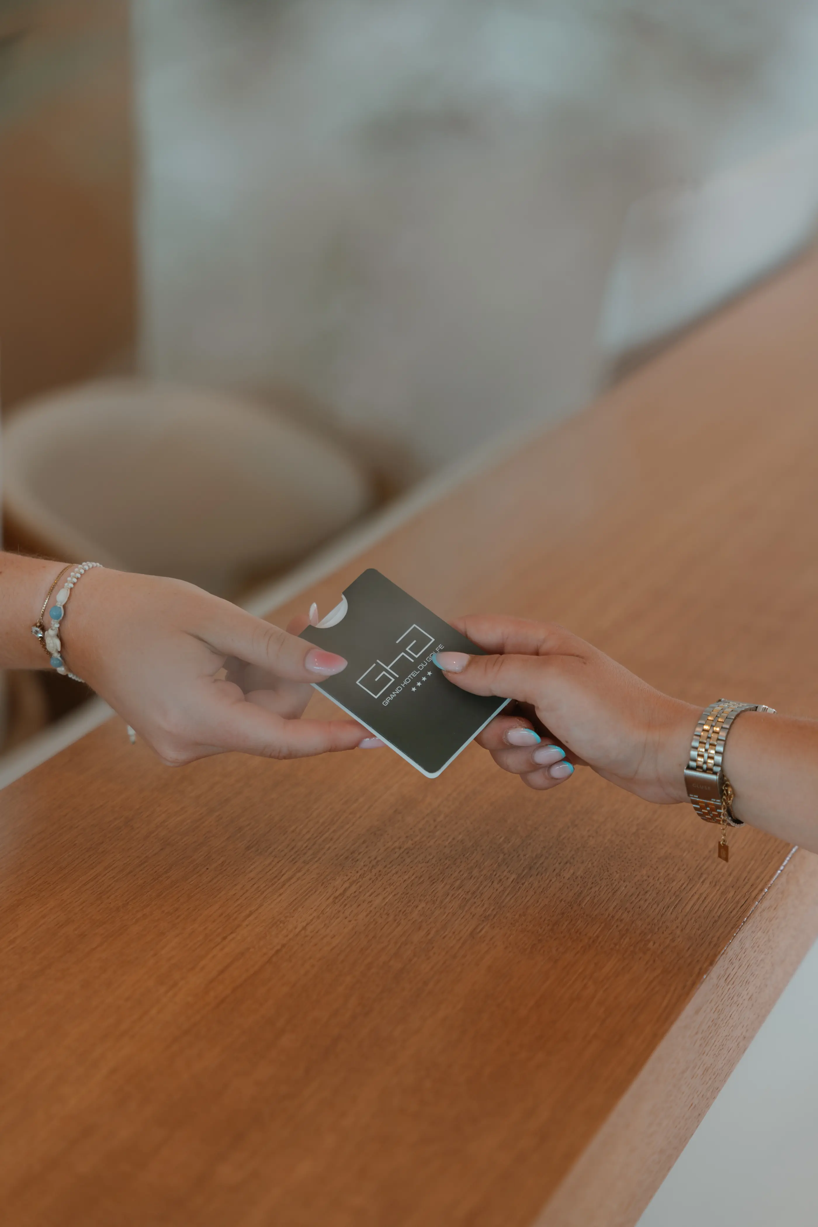 Deux mains échangent une carte d'hôtel sur une table en bois