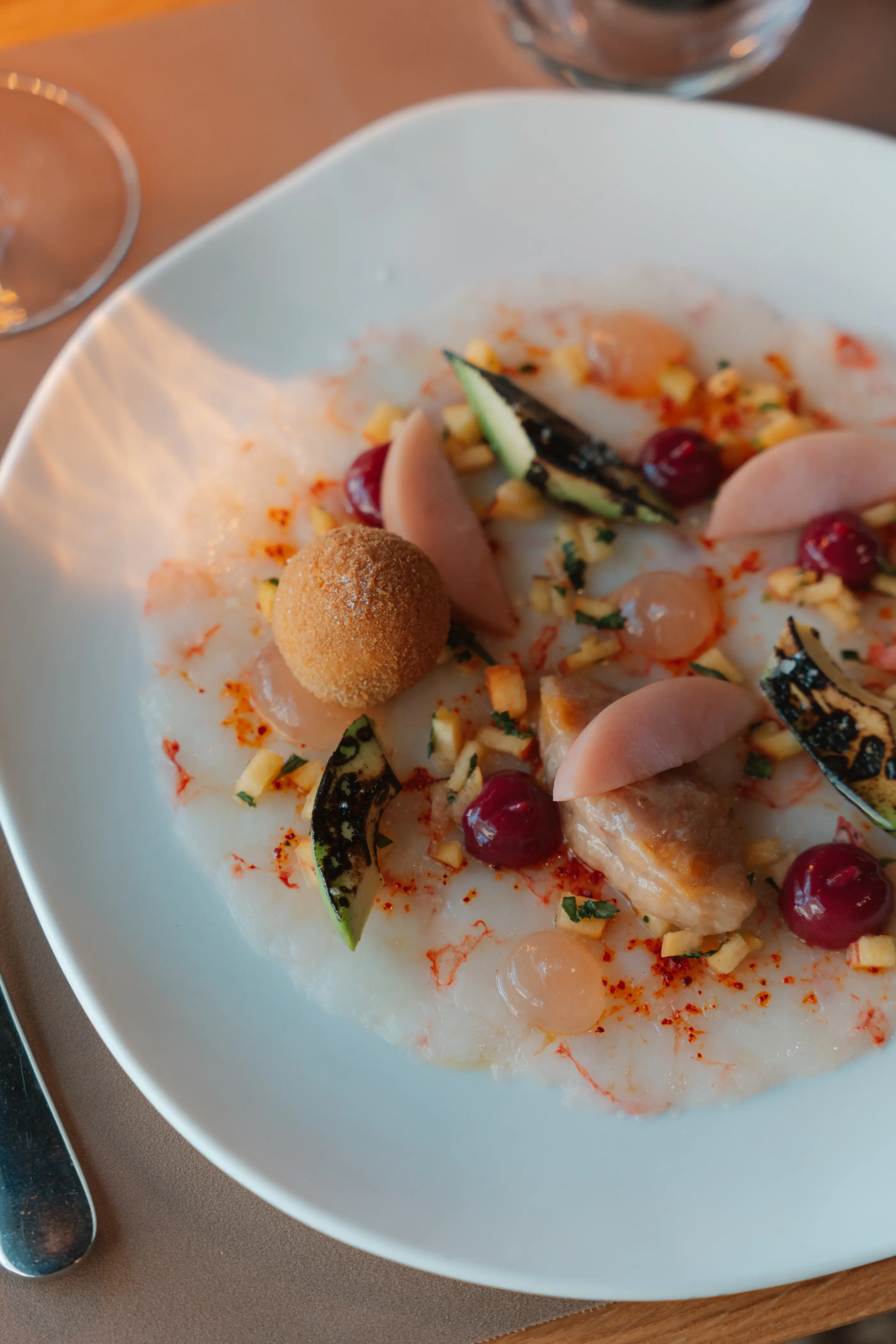 Un plat de fruits de mer avec des coquillages, des crevettes, des légumes et des fruits, présenté sur une assiette blanche avec une sauce blanche et des épices